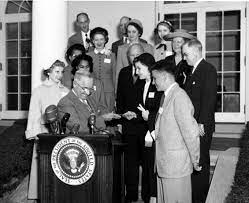 President Truman is pictured with several individuals around a podium after approving a Congressional resolution declaring the first week in October “National Employ the Physically Handicapped Week.”
